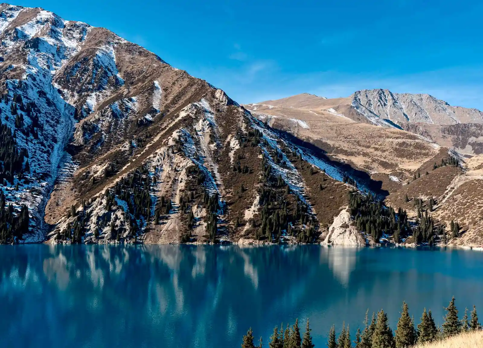Big Almaty Lake with turquoise water reflecting the surrounding rocky mountain slopes